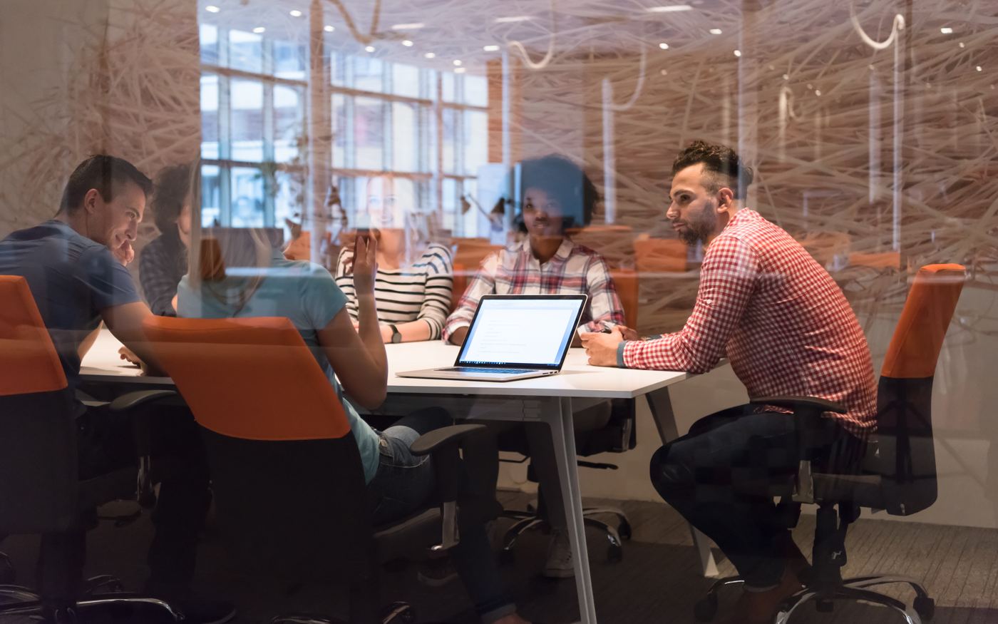People discussing plans around a meeting table with a laptop