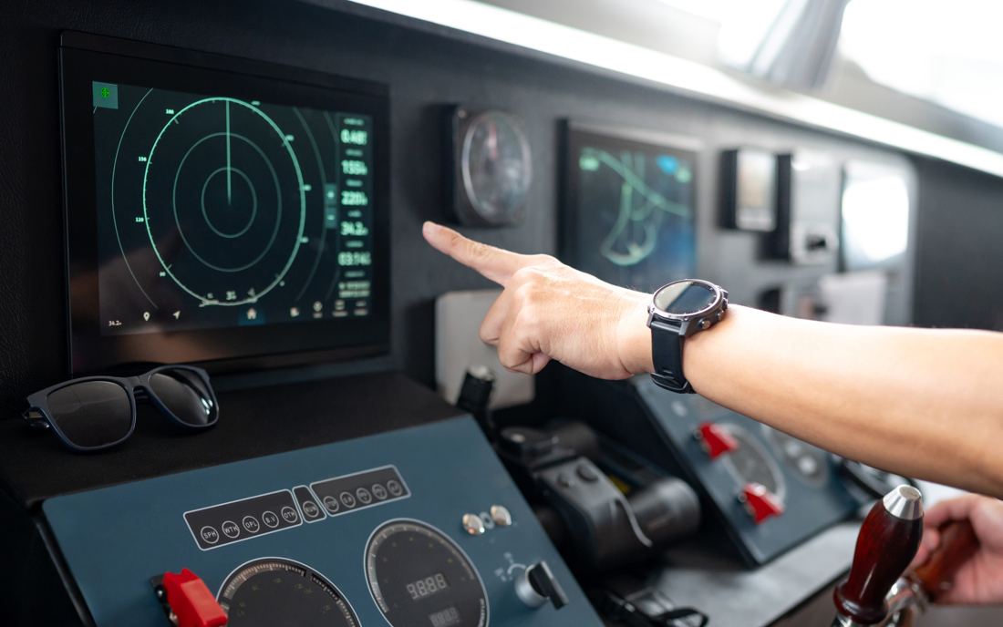 A hand pointing at a marine radar display