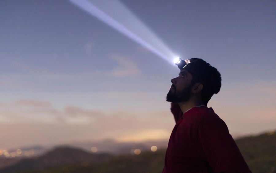 Person with a headlamp looking up at the evening sky