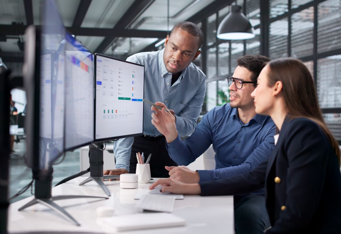 A finance team reviewing dashboards across two monitors