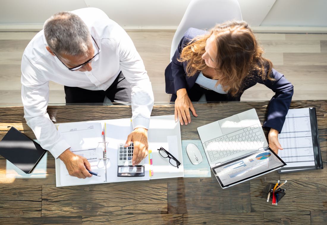 Two people planning over documents at a work table, seen from above