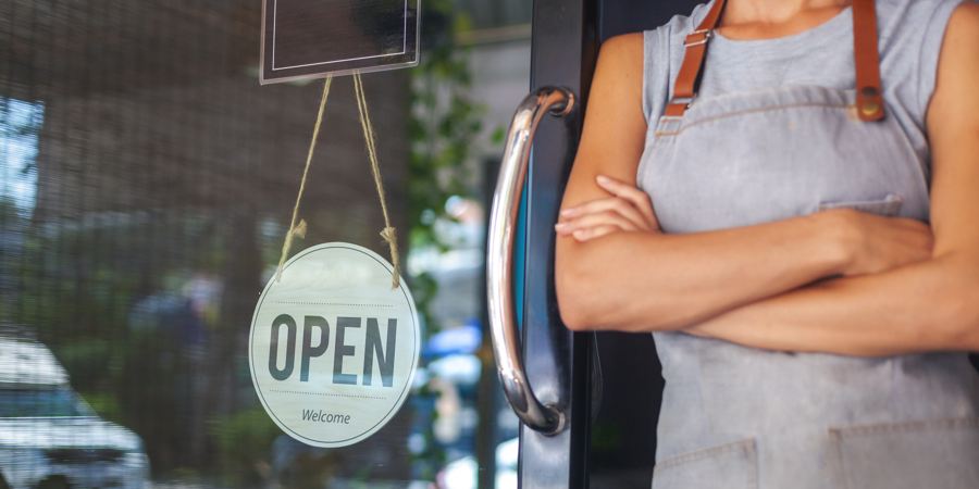 A shop owner turning the OPEN sign on their storefront door
